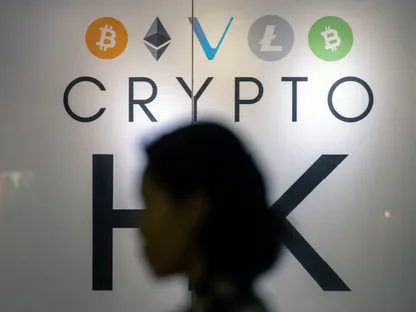 سيدة تعبر من أمام لوحة تعرض شعارات لعملات رقمية مختلفة، هونغ كونغ، الصين - المصدر: بلومبرغ