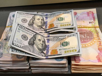 أوراق نقدية من فئة 100 دولار فوق حزمة من الأوراق النقدية العراقية من فئة 5000 و25000 دينار - المصدر: وكالة الأنباء العراقية