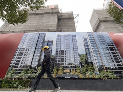 شخص يمر أمام عمارات ضمن مشروع قيد الإنشاء في شنغهاي  - المصدر: بلومبرغ