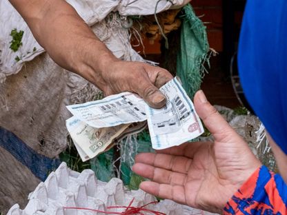زبون يدفع نقوداً ورقية لتاجر داخل أحد أسواق المواد الغذائية بمنطقة الدرب الأحمر بالقاهرة، مصر - المصدر: بلومبرغ