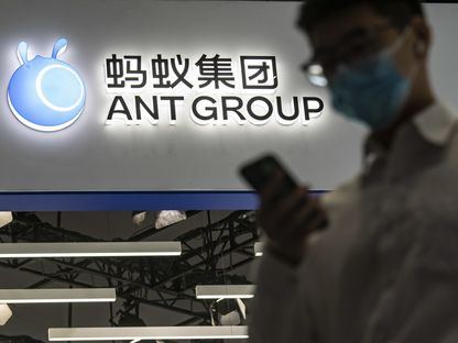 شخص يعبر من أمام لوحة مضاءة تحمل شعار شركة \"آنت غروب\" الصينية - المصدر: بلومبرغ