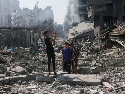 فلسطينيون على أنقاض مباني مهدومة بعض غارات جوية على مدينة غزة  - أ.ب.