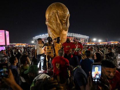 مشجعو فريقي غانا والبرتغال يتجمعون لالتقاط صور تذكارية أمام مجسم لكأس العالم في الدوحة. قطر - الشرق/بلومبرغ