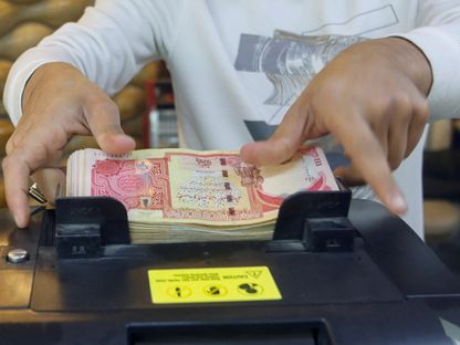 رجل يستخدم آلة لعد أوراق نقدية عراقية في محل صرافة في بغداد. العراق. في 23 يناير 2023 - المصدر: رويترز