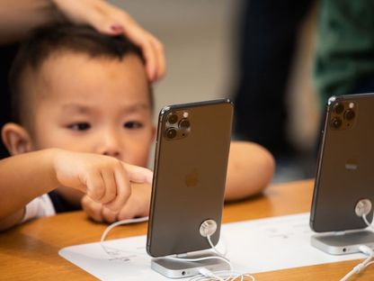 طفل يحاول استخدام هاتف ذكي من \"أبل\" في متجر \"أبل\" في هونغ كونغ، الصين - المصدر: بلومبرغ