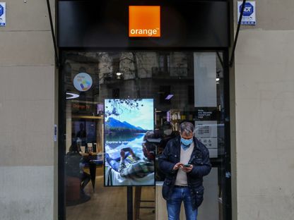 مستخدم هاتف ذكي خارج أحد متاجر \"أورانج\" في برشلونة - المصدر: بلومبرغ