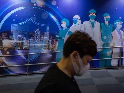 أحد الأشخاص يسير أمام لوحة جدارية تصور عمال الرعاية الصحية في هونغ كونغ.. مازالت الصين تشدّد الإجراءات ضمن حملة \"صفر كوفيد\" - المصدر: بلومبرغ