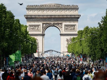 سياح يسيرون في شارع الشانزليزيه، بينما يهيمن قوس النصر على الأفق، خلال يوم \"خالٍ من السيارات\" في باريس في 4 مايو 2025 - Getty Images