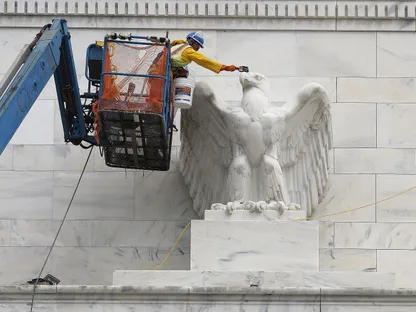 عامل ينظف تمثال النسر على مبنى مجلس الاحتياطي الفيدرالي في واشنطن - بلومبرغ