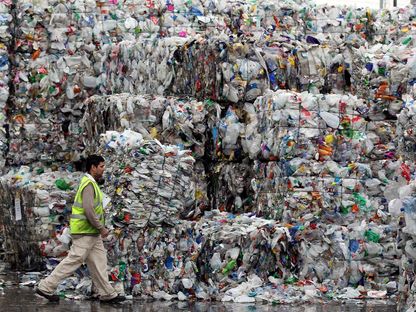 أحد موظفي مصنع \"Closed Loop Recycling\" يسير بجوار أكوام من نفايات الزجاجات البلاستيكية في داغنهام، لندن، المملكة المتحدة - المصدر: غيتي إيمجز