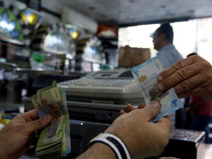 زبون يدفع ثمن مشترياته بالليرة السورية داخل متجر للحلويات في دمشق، سوريا (صورة غير مؤرخة) - رويترز 