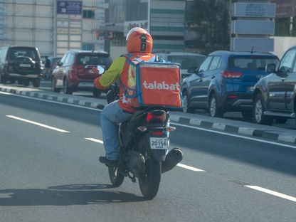 سائق يعمل في شركة \"طلبات\" في طريقه لتوصيل طلبية على متن دراجة نارية في أحد شوارع الدوحة، قطر - المصدر: غيتي إيمجز