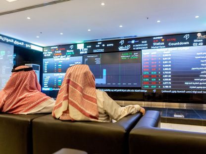 شخصان يتابعان معلومات أسعار الأسهم المعروضة على شاشة رقمية داخل السوق المالية السعودية (تداول) - صورة أرشيفية - المصدر: بلومبرغ