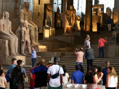 سياح ينظرون إلى التماثيل الفرعونية المعروضة على الدرج الكبير للمتحف المصري الكبير في الجيزة، مصر، 15 أكتوبر 2024 - رويترز