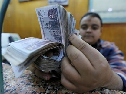 موظف يعد أوراقاً نقدية من فئة 50 جنيهاً في أحد مكاتب الصرافة وسط القاهرة. مصر - المصدر: بلومبرغ
