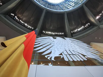 صورة من داخل مبنى \"الرايخستاغ\" في برلين، المقر الرئيسي للبرلمان الألماني (البوندستاغ). يظهر تحت قبة المبنى النسر الفيدرالي الألماني، الرمز الرسمي للجمهورية الألمانية، والعلم الوطني للبلاد - بلومبرغ