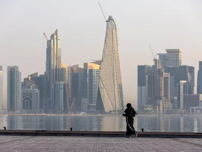 سيدة تمارس رياضة الركض على الكورنيش مع أفق المدينة الشاهق في الخلفية في الدوحة، قطر - بلومبرغ