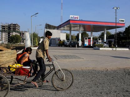 راكب دراجة يمر من أمام محطة غاز تابعة لـ\"أداني غروب\" في أحمد آباد، الهند. - المصدر: بلومبرغ