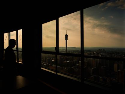 رجل ينظر من نافذة مبنى مرتفع باتجاه الأفق - المصدر: بلومبرغ