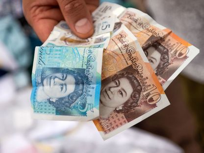 بائع يحمل أوراق نقدية من فئة عشرة وخمسة جنيهات إسترليني في أحد المحلات بمنطقة باركينج، المملكة المتحدة - المصدر: بلومبرغ