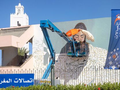 الفنانة المغربية إيمان دروبي تعمل على لوحة جدارية خلال مهرجان فنون الشارع في الرباط - المصدر: غيتي إيمجز