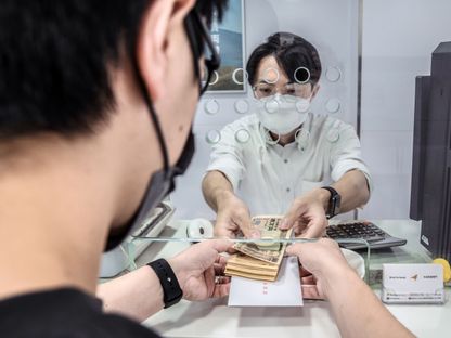 أحد الموظفين يسلّم حزمة أوراق مالية فئة 10 آلاف ين لزميله بإحدى شركات الصرافة في هونغ كونغ، الصين - المصدر: بلومبرغ