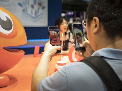 شخص يصور هاتف \"رينو\" من إنتاج \"أوبو\" - في اليد اليسرى- بأحد الهواتف الأخرى بمعرض \"ام دبليو سي شنغهاي\" في شنغهاي، الصين - المصدر: بلومبرغ