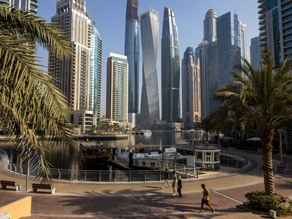 مشاة يمرون عبر المارينا، وفي الخلفية ناطحات السحاب السكنية والتجارية في منطقة مرسى دبي، دبي، الإمارات العربية المتحدة - المصدر: بلومبرغ