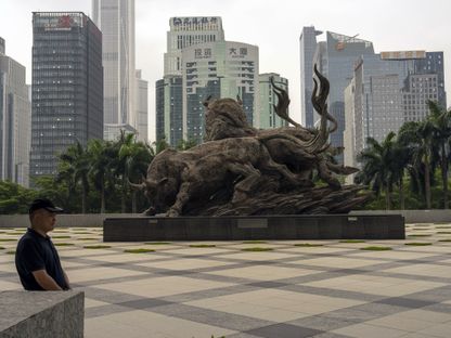 رجل يمر أمام تمثال ثور عند مبنى بورصة شنتشن في شنتشن، الصين - المصدر: بلومبرغ