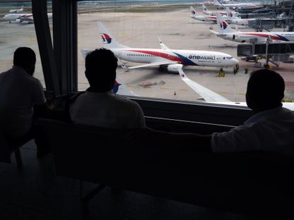 ركاب ينتظرون أمام نافذة في مطار \"كوالالمبور الدولي\"، ماليزيا - المصدر: بلومبرغ