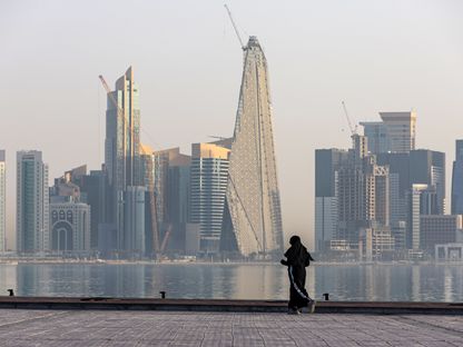 سيدة تمارس رياضة الجري على كورنيش في الدوحة، ويبدو في الأفق ناطحات سحاب سكنية وتجارية، في العاصمة القطرية - المصدر: بلومبرغ
