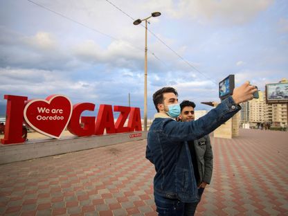 شابان فلسطينيان يلتقطان صورة \"سيلفي\" قرب شاطئ مدينة غزة - المصدر: بلومبرغ