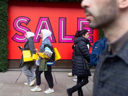 المتسوقون يمررون لافتات ترويجية للبيع في متجر \"سيلفريدجز آند كو\" خلال مبيعات عطلة عيد الميلاد التقليدية، في لندن بالمملكة المتحدة - المصدر: بلومبرغ