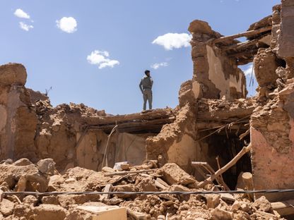 مواطن يقف فوق أنقاض مبانٍ مدمرة بمنطقة الحوز إثر الزلزال الذي ضرب المغرب - المصدر: بلومبرغ