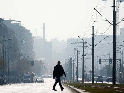 شخص يعبر شارعاً ويبدو الجو في المنطقة ملوثاً بالإنبعاثات الكربونية - الشرق/بلومبرغ