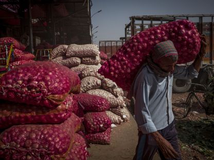 عامل يحمل كيساً من البصل في سوق للجملة في نيودلهي، الهند - المصدر: بلومبرغ