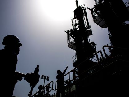 عمّال يشاركون في عمليات الغاز الطبيعي المُسال من السفينة إلى السفينة في محطة \"فاوجي أويل ترمينال آند ديستريبيوشن\" (Fauji Oil Terminal & Distribution Co. Ltd. ) في كراتشي، باكستان. - المصدر: بلومبرغ