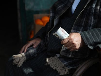 عميل يمسك بأوراق نقد مصرية في سوق العبور للجملة - المصدر: بلومبرغ