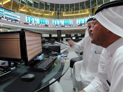 شخصان أمام شاشة تداول داخل بورصة البحرين - المصدر: بلومبرغ