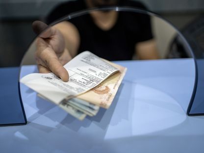 موظف يسلم أحد العملاء أوراقًاً نقدية بالليرة التركية في بورصة عملات في أنقرة، تركيا. - المصدر: بلومبرغ
