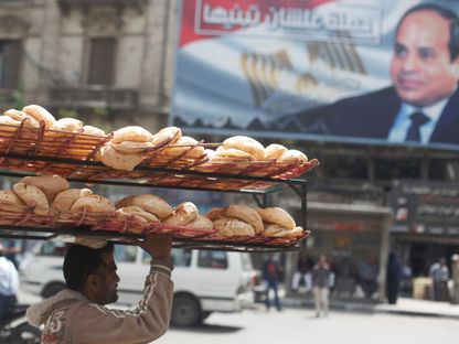 رجل يحمل الخبز على رأسه بالقرب من لافتة تحمل صورة للرئيس المصري عبد الفتاح السيسي. القاهرة. مصر - المصدر: رويترز