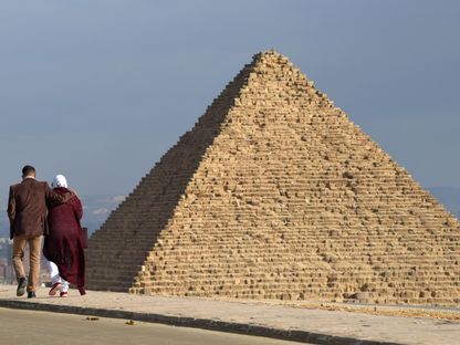 زوجان يسيران على طريق قرب هرم في الجيزة، مصر - المصدر: بلومبرغ