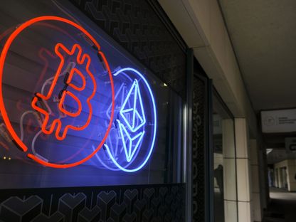 شعارات مضاءة بالنيون ترمز للعملات المشفرة \"بتكوين\" و\"إيثر\" في نافذة بورصة العملات المشفرة في وارسو، بولندا - المصدر: بلومبرغ