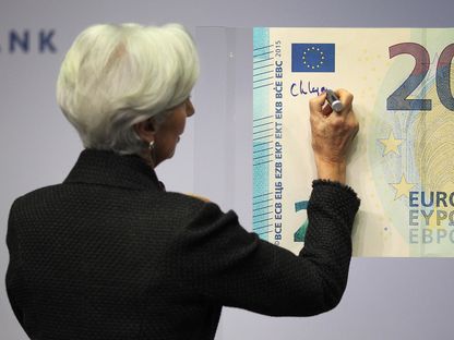 رئيسة البنك المركزي الأوروبي كريستين لاغارد توقع على مجسم عملاق لليورو - المصدر: غيتي إيمجز