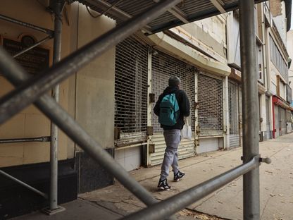 شخص يمشي أمام محل تجاري مغلق في نيوارك ، نيو جيرسي ، الولايات المتحدة  - المصدر: بلومبرغ