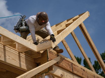 عامل في موقع بناء يقوم بتركيب القطع الخشبية على الهيكل - المصدر: بلومبرغ