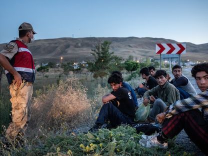 أحد الضباط يراقب مهاجرين تم ضبطهم في سيارة مهربين في مدينة فان بتركيا  - المصدر: بلومبرغ