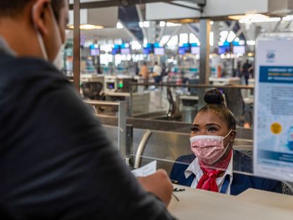 موظفة في شركة طيران تقوم بتسجيل وصول مسافر من خلف شاشة بلاستيكية واقية داخل صالة المغادرة في مطار كيب تاون الدولي في كيب تاون، جنوب أفريقيا، يوم الأربعاء، 31 مارس 2021. ساهم السفر والسياحة بنسبة 7% في الناتج المحلي الإجمالي لجنوب إفريقيا في أوقات ما قبل الجائحة، وفقاً لمجلس السفر والسياحة العالمي. - المصدر: بلومبرغ