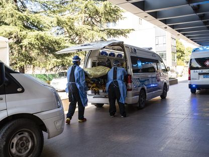 مسعفون ينقلون مصابين بكوفيد عبر سيارة إسعاف لتلقي العلاج، الصين - المصدر: بلومبرغ