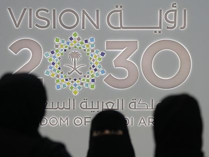 سيدات يقفن أمام شعار رؤية 2030 خلل مؤتمر بالعاصمة السعودية الرياض (أرشيفية) - المصدر: بلومبرغ